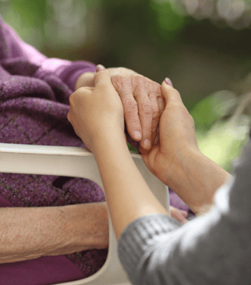 A caregiver holding a senior's hand in a caring gesture