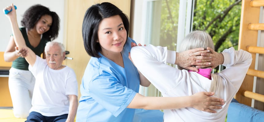 Staff assisting residents with exercises in a therapy room
