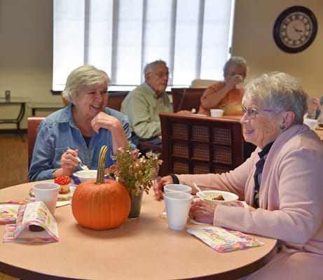 Residents enjoying a meal and sharing smiles in a common area