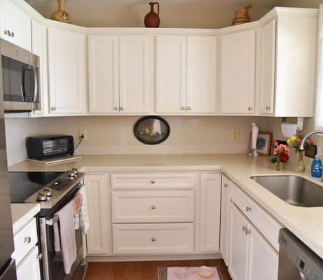 Bright kitchen area with white cabinets and modern appliances