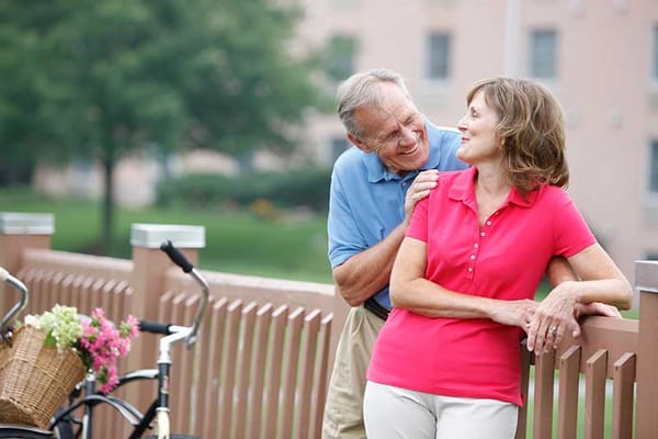 Couple enjoying time together by a fence in a green outdoor space