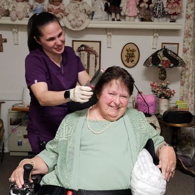 Staff member styling resident's hair in a cozy room