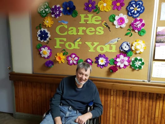 Resident sitting in front of a colorful bulletin board