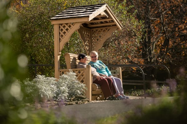 Two residents enjoying a sunny outdoor space on a bench