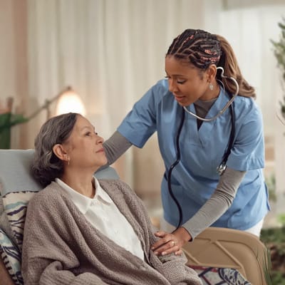 A caregiver assisting a senior resident in a cozy room