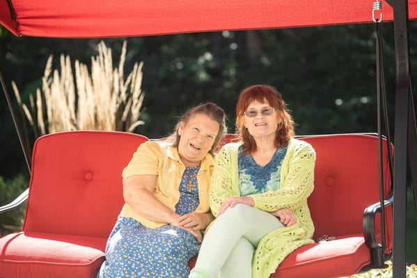 Two residents enjoying time outdoors on a swing