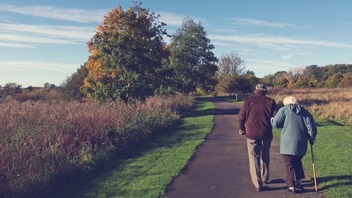 Two seniors walking along a scenic path