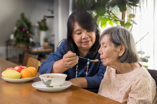 Caregiver feeding a senior resident in a welcoming indoor space