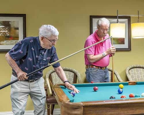 Two residents playing billiards in a common area