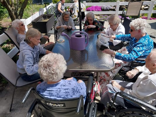 Residents enjoying an outdoor activity at a table with flowers