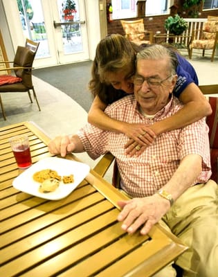 A staff member hugs a resident while sharing cookies.