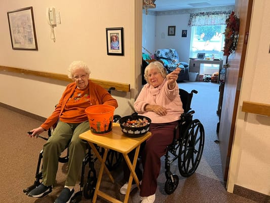 Two residents in wheelchairs engaging with Halloween decorations