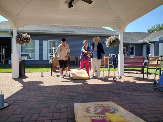 Residents and staff playing cornhole outdoors