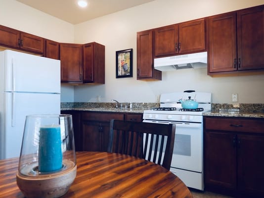 Bright kitchen area with wooden cabinets and a blue kettle