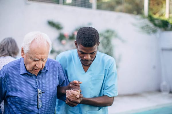 Caregiver assisting an elderly man outdoors