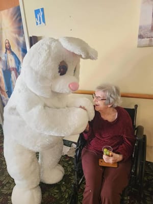 A resident interacting with a costumed bunny in the hallway
