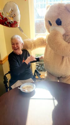 Resident enjoying a meal with a teddy bear mascot