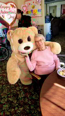 Resident enjoying time with a large teddy bear in a cozy setting