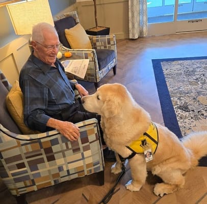 Resident interacting with a therapy dog in a cozy lounge area