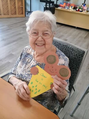 Resident happily holding a colorful craft project