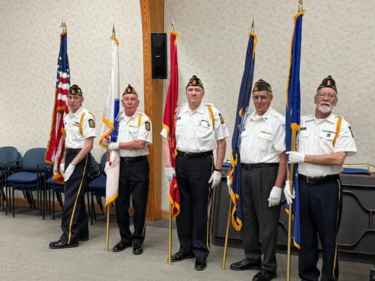 Veterans holding flags in an indoor ceremony