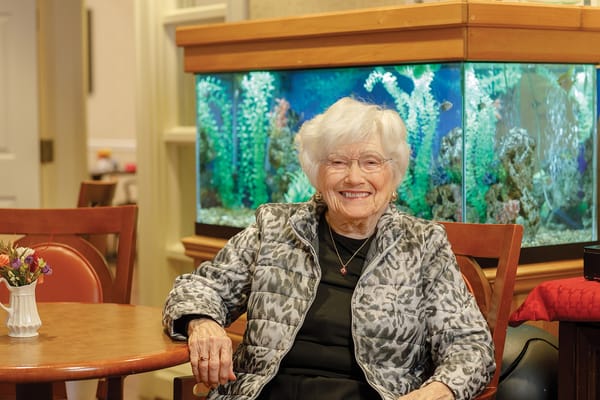 Resident smiling in front of an aquarium in a common area