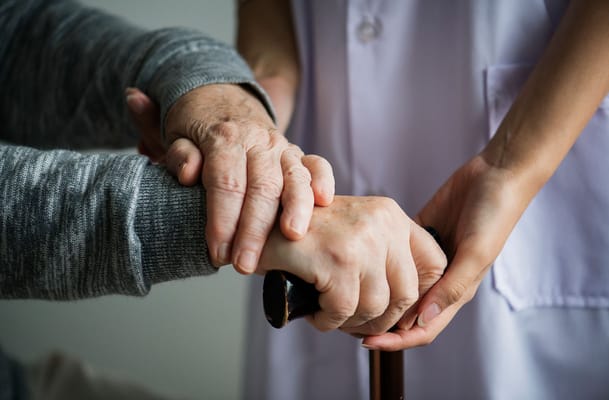 Caregiver and elderly resident holding hands