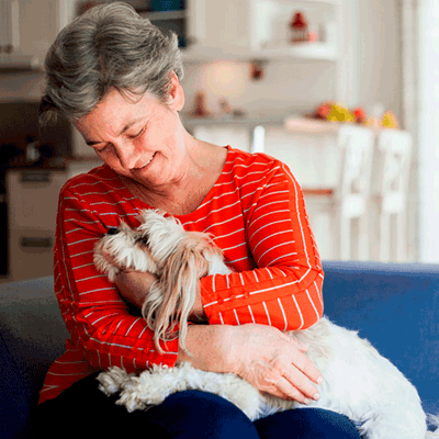 Senior woman cuddling with a small dog in a cozy living space