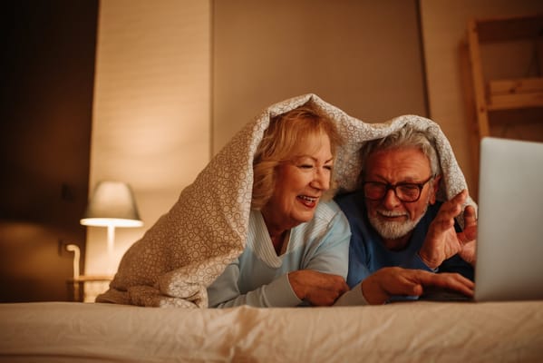 Senior couple enjoying a cozy moment on a bed with a laptop