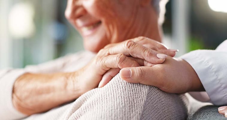 Close-up of a caregiver's hand on a senior's shoulder