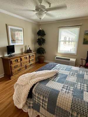 Interior view of a resident's bedroom with a bed and dresser