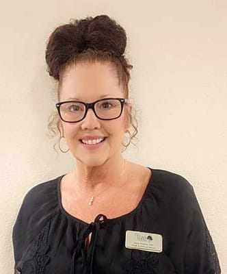 Staff member smiling in a black top with name badge