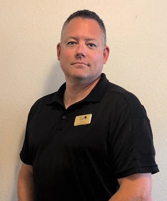 Staff member posing in front of a plain wall