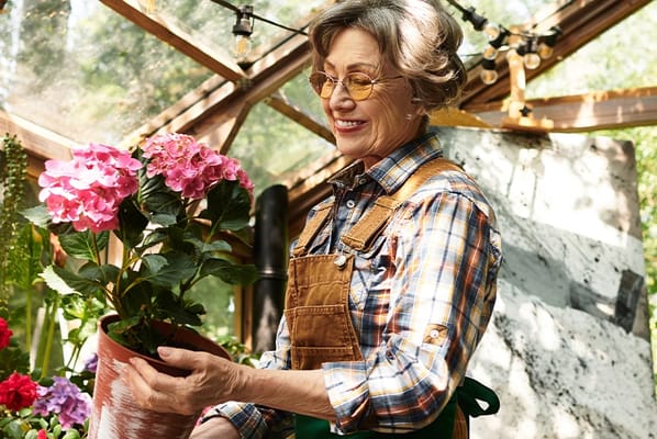 Senior woman tending to flowers in a greenhouse