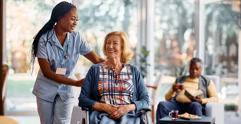 A caregiver assisting a resident in a bright common area