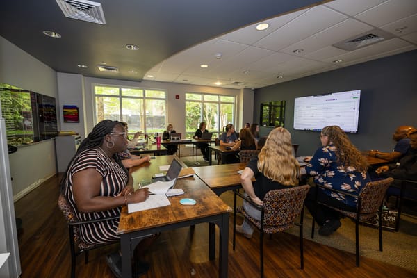 Staff meeting in a bright interior room with large windows