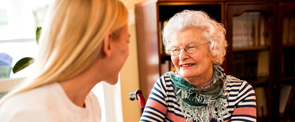 Elderly resident smiling with caregiver in a cozy setting