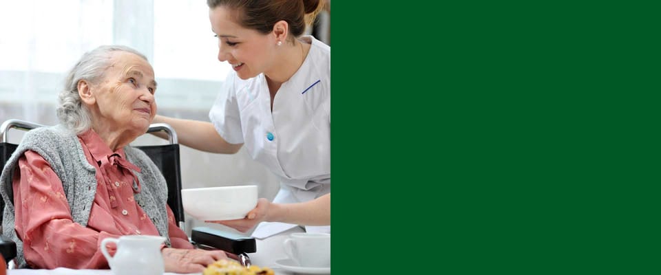 A caregiver serving a meal to a resident in a dining setting