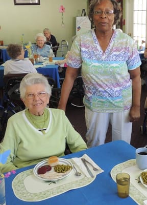 Resident enjoying a meal with staff in a dining area