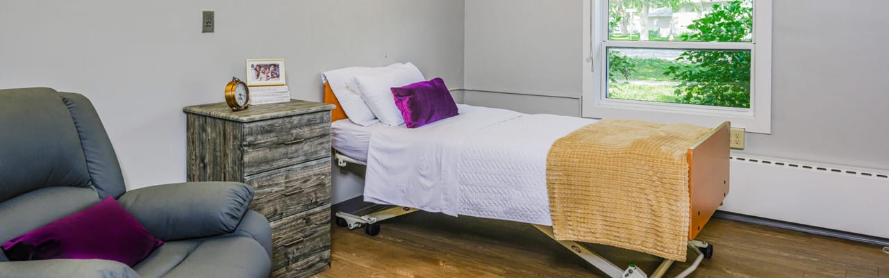 A cozy resident room featuring a bed and chair