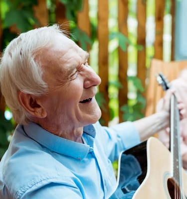 Elderly man playing guitar and smiling