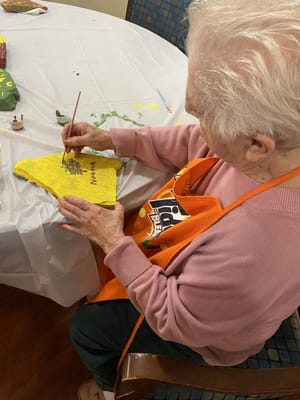 An elderly woman painting at a table during an activity