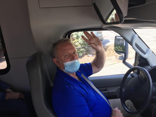 Driver waving from a facility transport vehicle