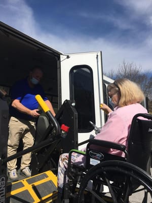 Staff assisting a resident in a wheelchair at the facility transport van