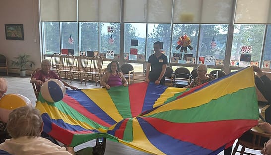 Residents engaging in a colorful group activity with a parachute