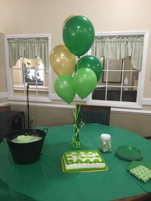 Celebration setup with balloons and a cake in a social space
