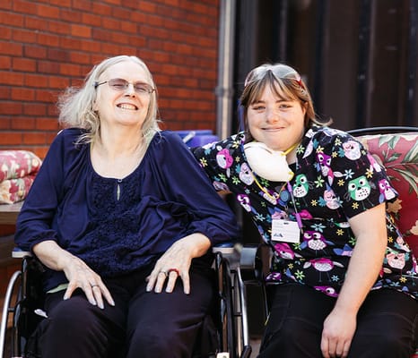 Resident and staff member smiling together outdoors