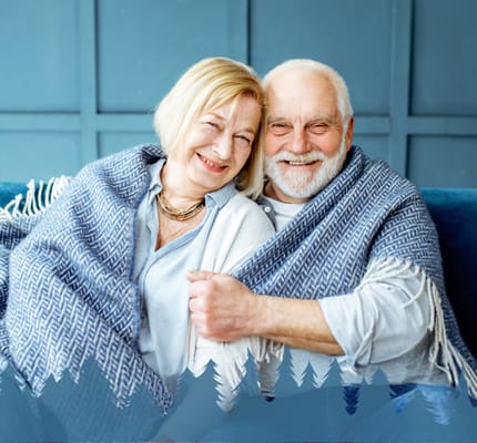A smiling elderly couple wrapped in a blanket