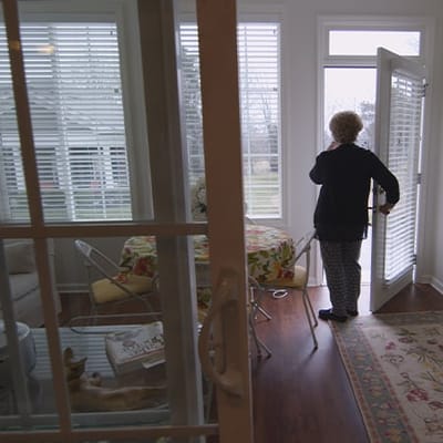 Resident entering a sunlit room from a patio door