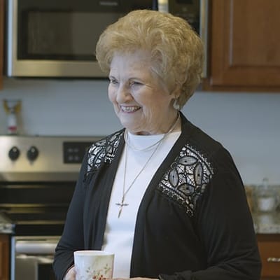 Smiling resident in a kitchen area with a mug